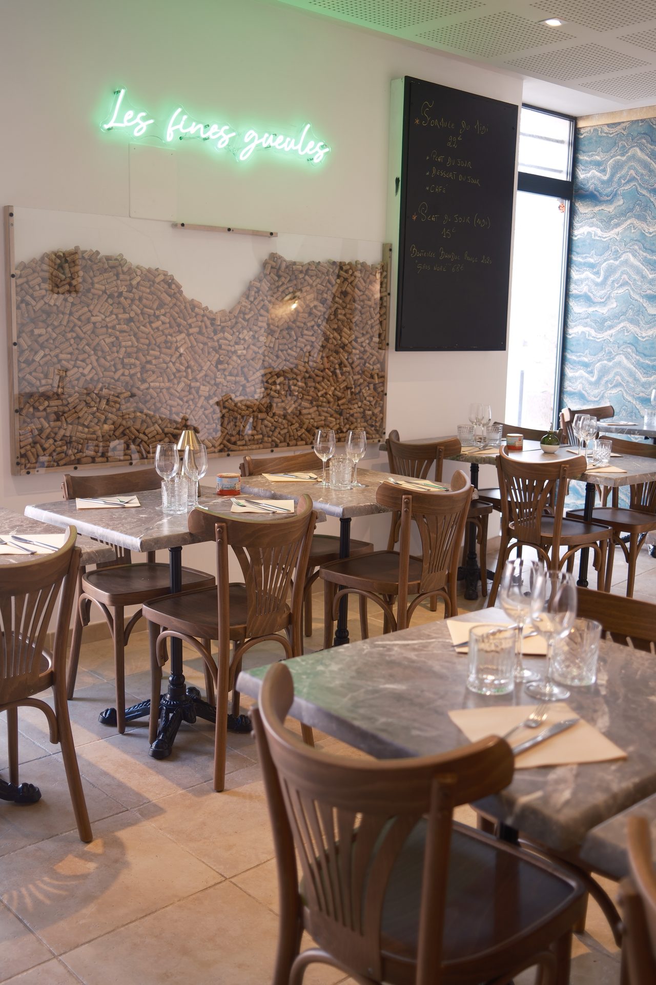 Vue large de la salle, tables marbre et chaises bistrot